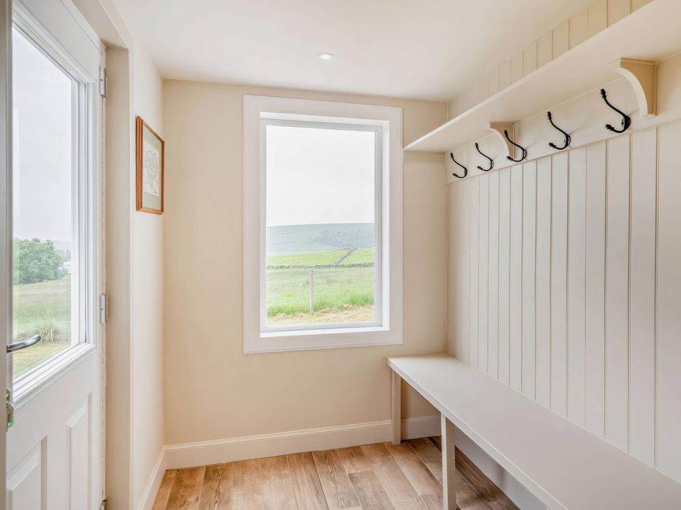 A hallway with a bench and wall hooks at Upper Hillside Cottage in Blairgowrie
