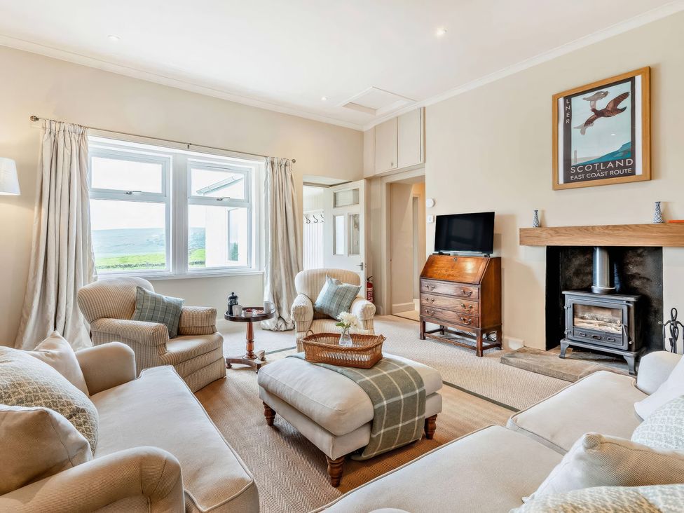 A living room with a sofa, armchairs, and a television at Upper Hillside Cottage in Blairgowrie