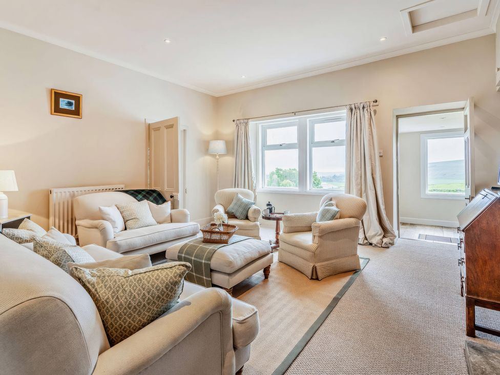 A living room with a sofa and chairs at Upper Hillside Cottage in Blairgowrie