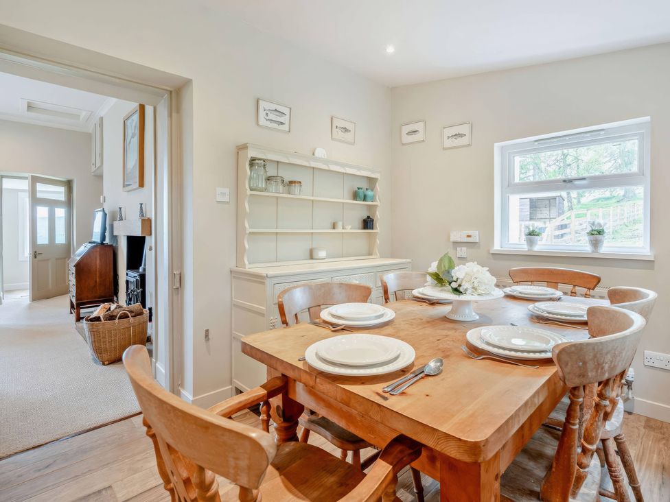 A dining room with a table set for six at Upper Hillside Cottage in Blairgowrie