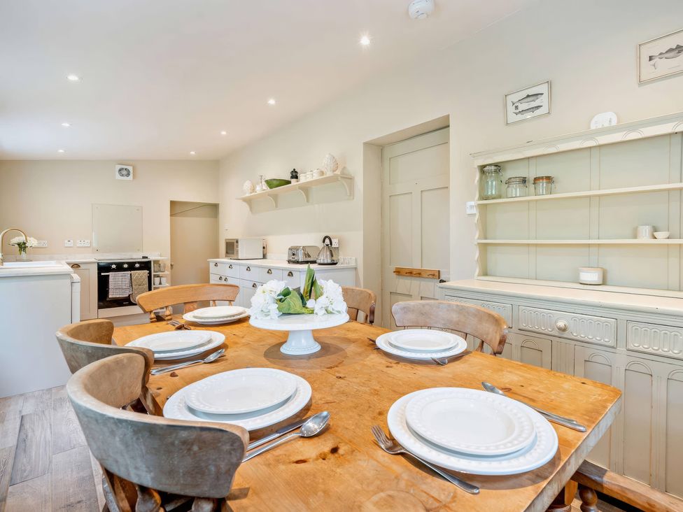 A kitchen with a wooden table and chairs at Upper Hillside Cottage in Blairgowrie