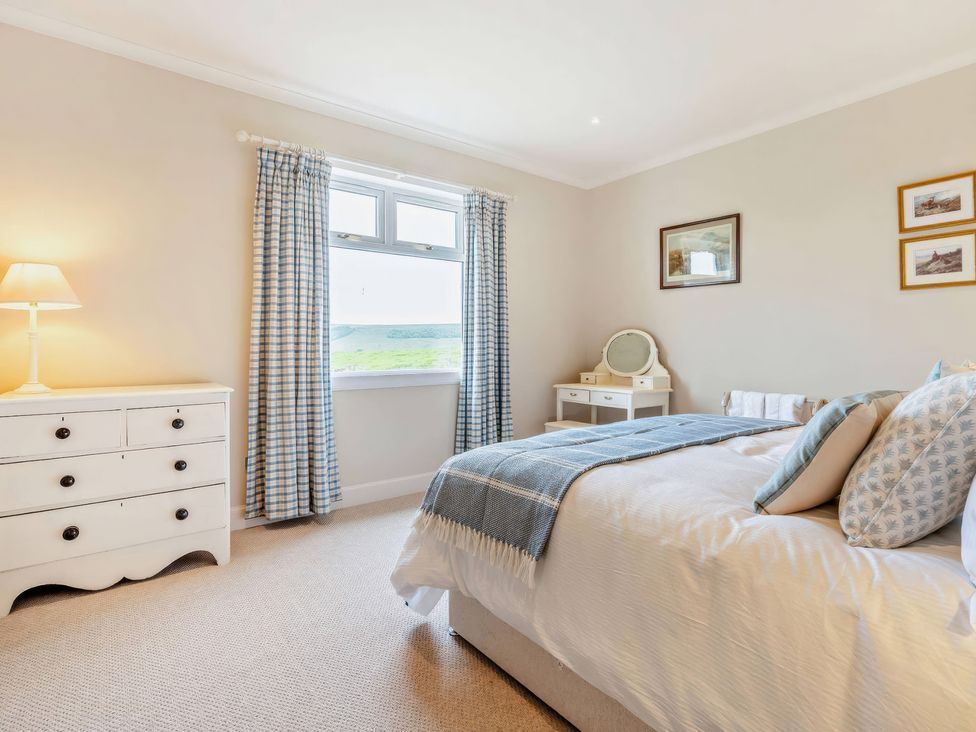 A bedroom with a bed and dresser at Upper Hillside Cottage in Blairgowrie