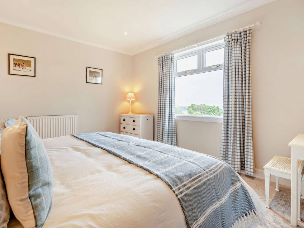 A bedroom with a bed and dresser at Upper Hillside Cottage in Blairgowrie