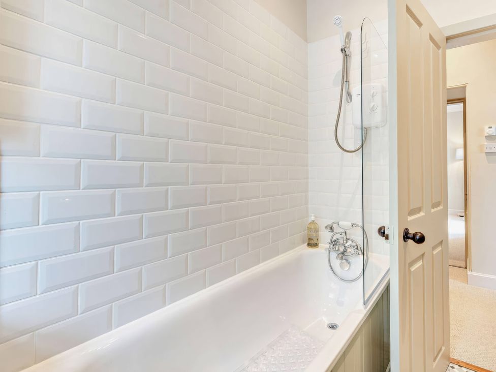 A bathroom with a bathtub and shower fixtures at Upper Hillside Cottage in Blairgowrie