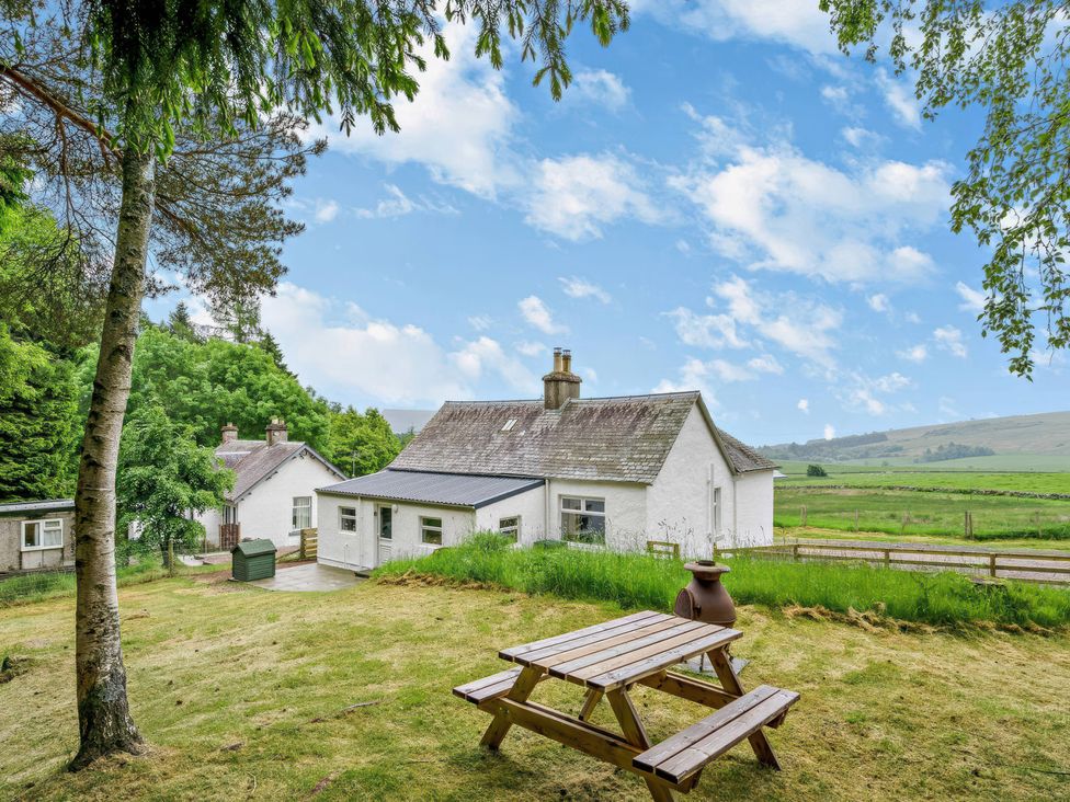 A house with a garden and seating area at Upper Hillside Cottage in Blairgowrie