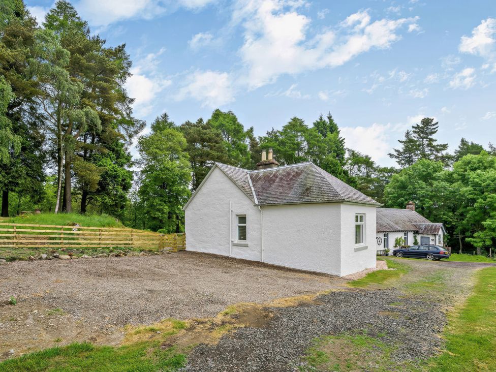 A house with a gravel area and trees at Upper Hillside Cottage in Blairgowrie