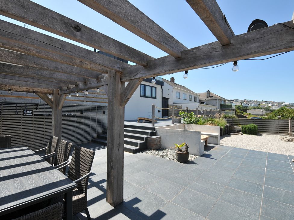 A garden with a wooden pergola and dining table at Breakers View in Polzeath