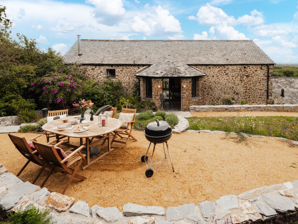 An outdoor dining area with a table and chairs at Hoppers Barn in Pancrasweek near Holsworthy