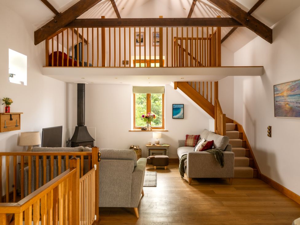 A living room with a staircase and window at Hoppers Barn Pancrasweek near Holsworthy