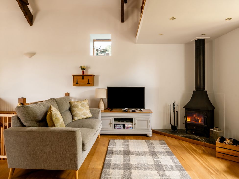 A living room with a sofa and a television at Hoppers Barn Pancrasweek near Holsworthy