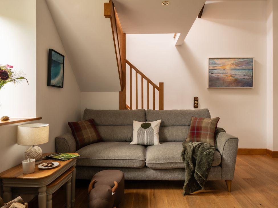 A living room with a sofa and a lamp at Hoppers Barn in Pancrasweek near Holsworthy
