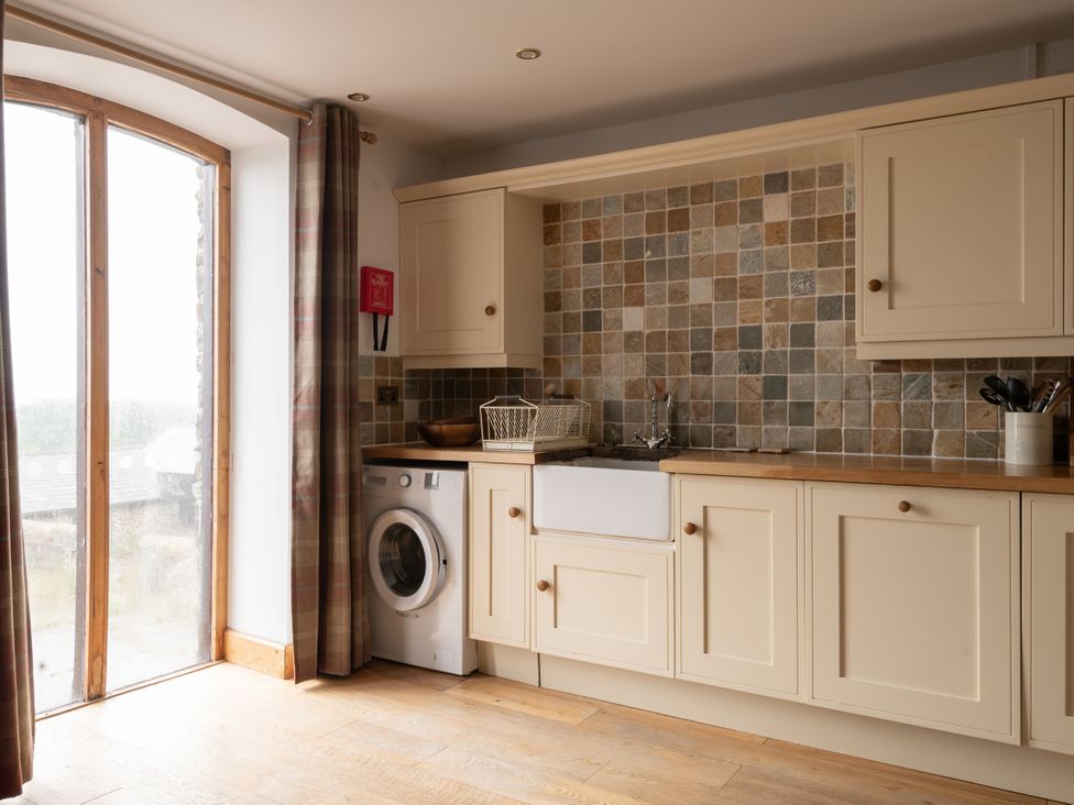 A kitchen with a washing machine and sink at Hoppers Barn Pancrasweek near Holsworthy