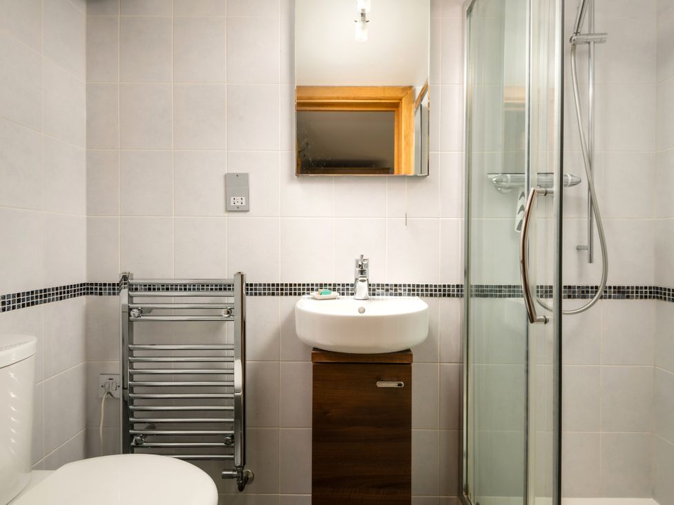 A bathroom with a sink, shower, and towel rail at Hoppers Barn near Holsworthy