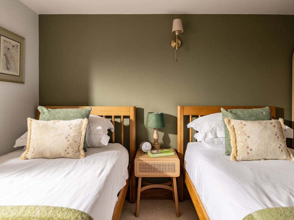 A bedroom with twin beds and a bedside table at Hoppers Barn Pancrasweek near Holsworthy