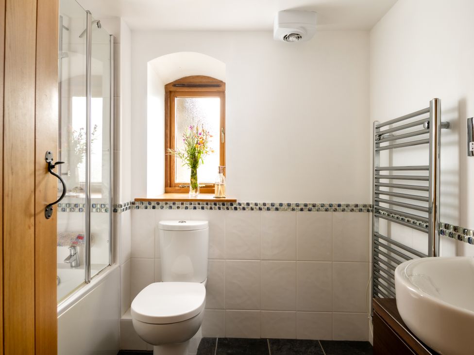 A bathroom with a shower, toilet, sink and window at Hoppers Barn in Pancrasweek near Holsworthy