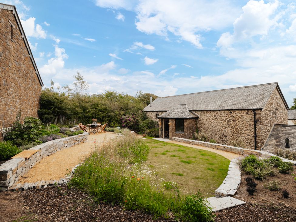 A garden area with seating and a stone pathway at Hoppers Barn Pancrasweek near Holsworthy