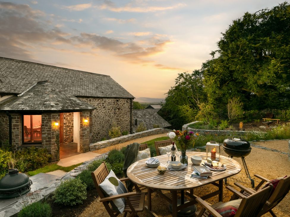 An outdoor dining area with a table and chairs at Hoppers Barn Pancrasweek near Holsworthy