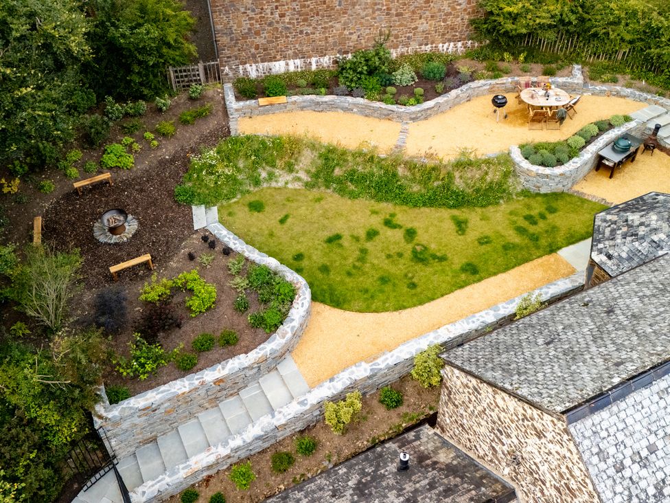 A garden with pathways and a fire pit at Hoppers Barn in Pancrasweek near Holsworthy