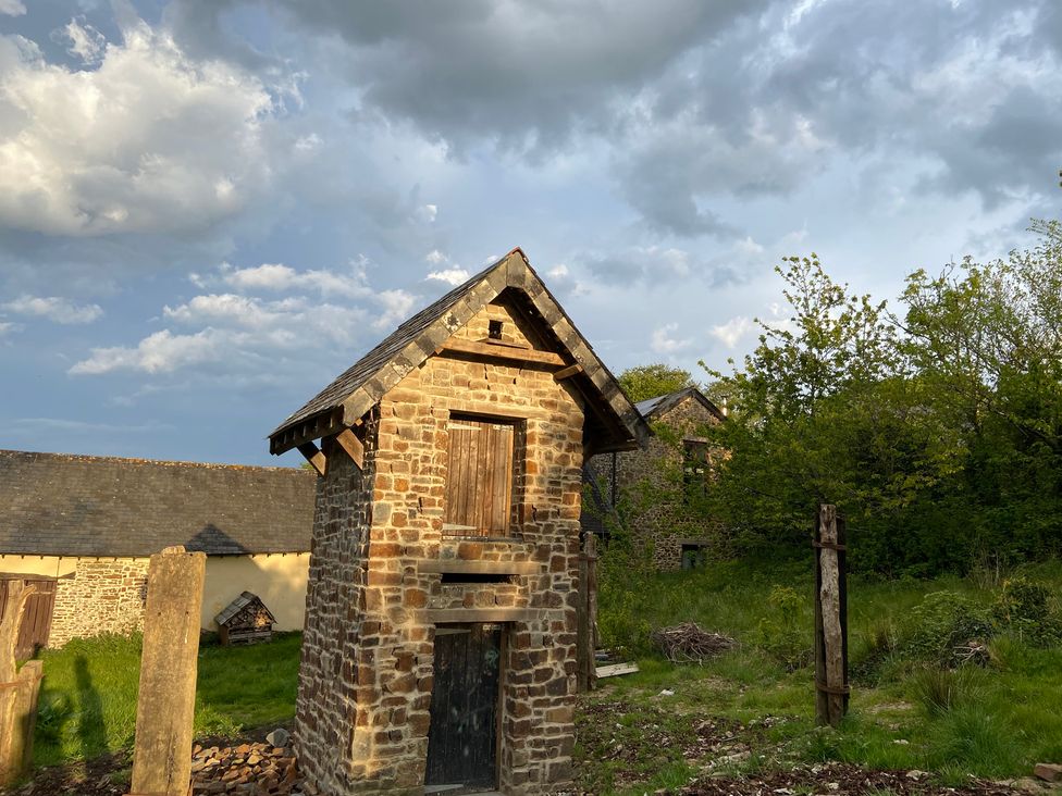 A stone building with wooden door and windows in a grassy area at Hoppers Barn Pancrasweek near Holsworthy