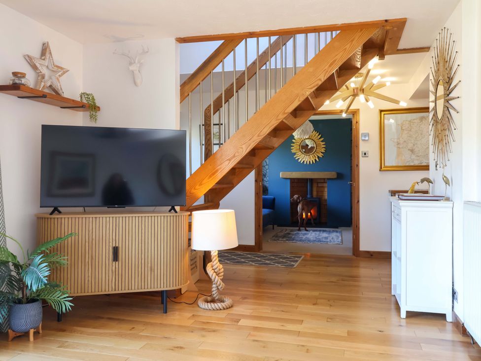 A living room with a television on a stand and a staircase at Hillsview in Combe Martin