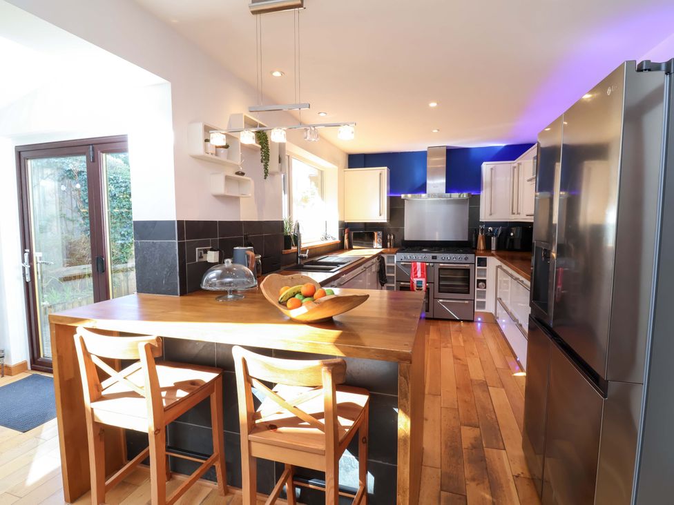 A kitchen with bar stools and stainless steel appliances at Hillsview in Combe Martin