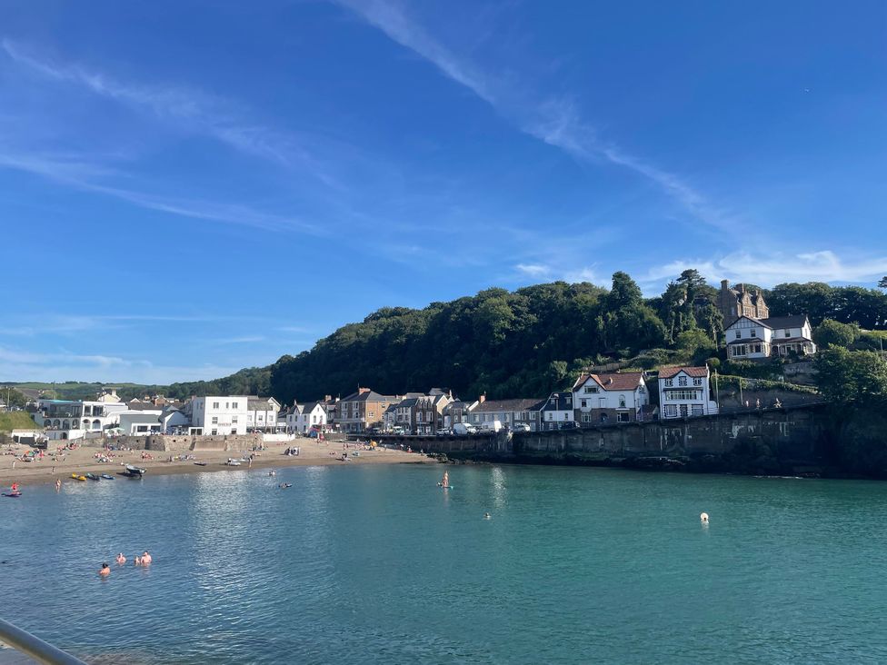 A beach with people and houses near the water at Hillsview in Combe Martin