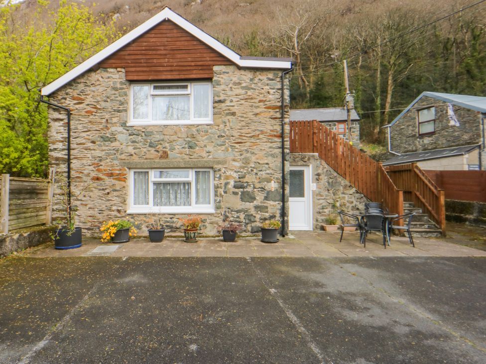 A stone building with planters and outdoor seating at First Floor Apartment in Tremadog