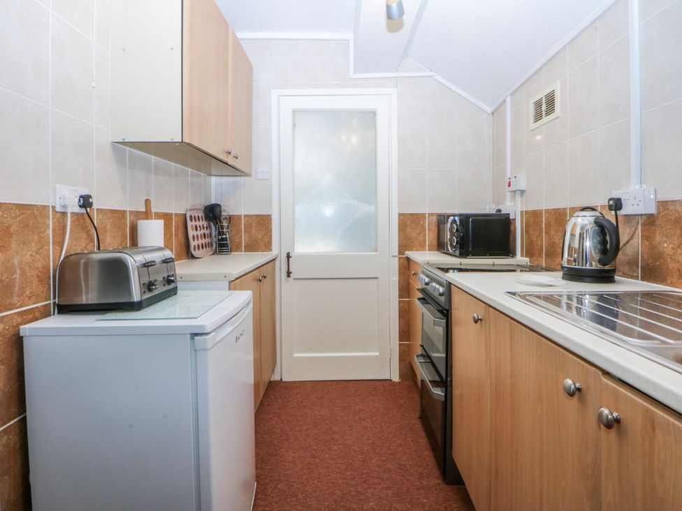 A kitchen with appliances and cabinets at First Floor Apartment in Tremadog