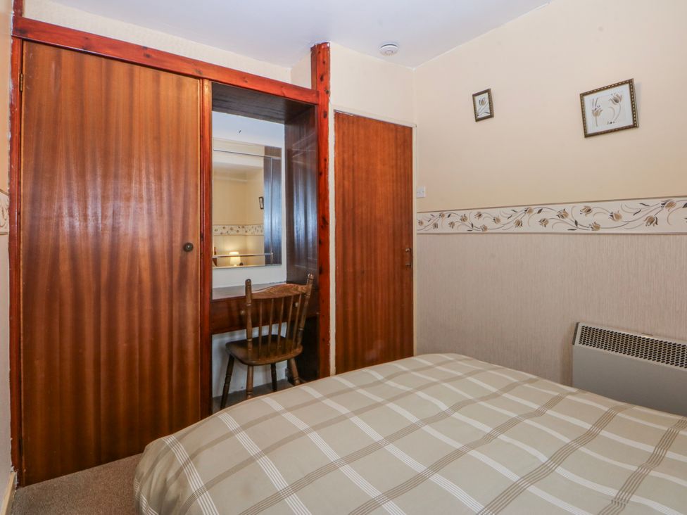 A bedroom with a bed, chair and mirror at First Floor Apartment in Tremadog