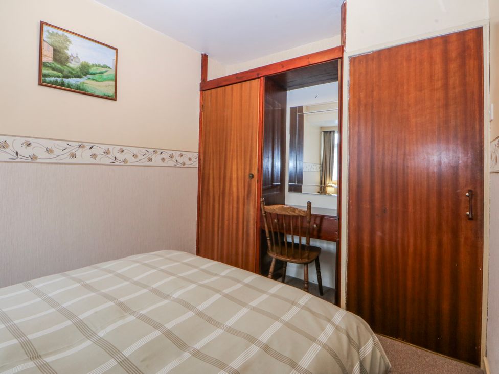 A bedroom with a bed and a chair at First Floor Apartment Tremadog