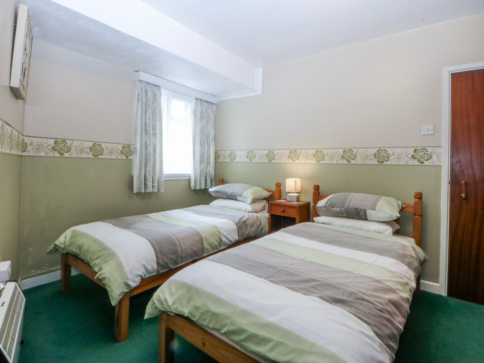 A bedroom with two beds and a bedside table at First Floor Apartment in Tremadog