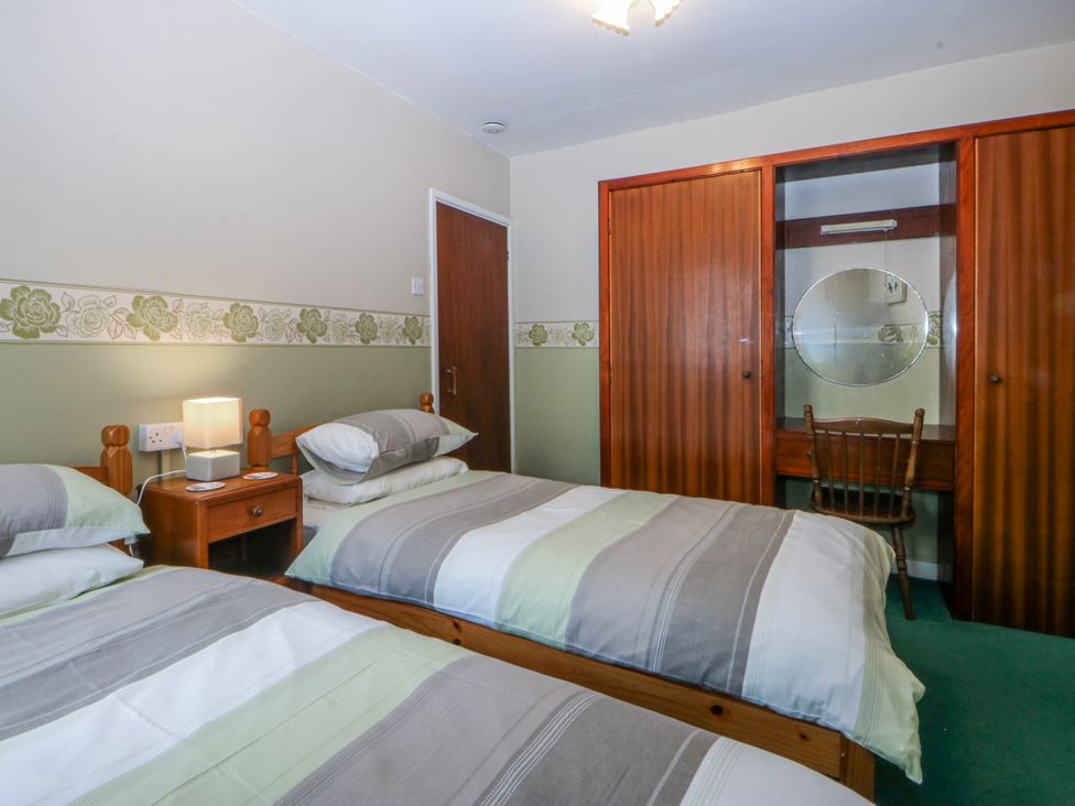 A bedroom with two beds and a wardrobe at First Floor Apartment in Tremadog