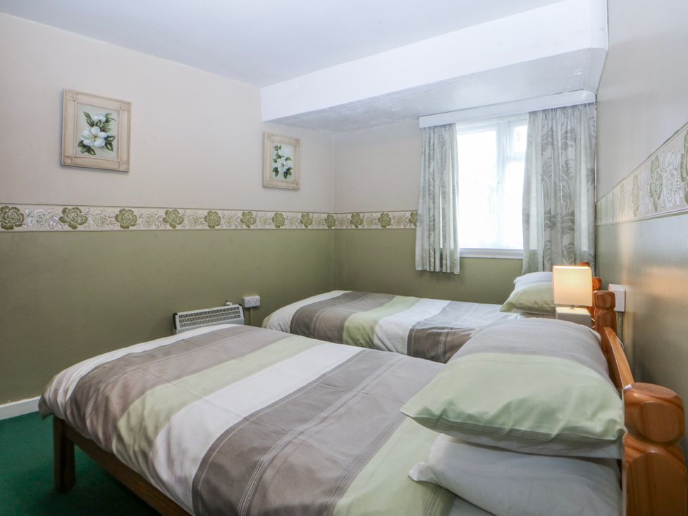 A bedroom with two beds and a window at First Floor Apartment in Tremadog