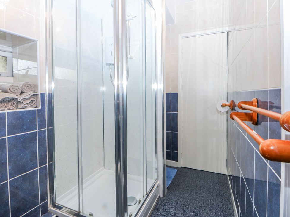 A bathroom with a shower and towels at First Floor Apartment in Tremadog