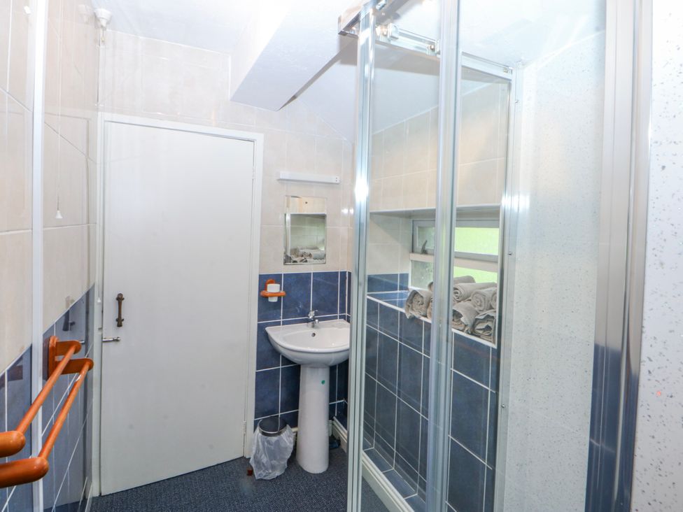 A bathroom with a shower, sink, and towels at First Floor Apartment in Tremadog