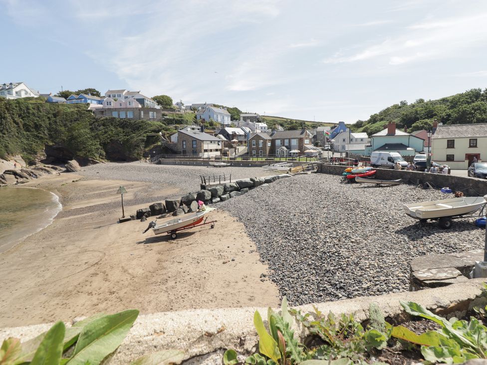 A beach view with boats and houses at Reef Retreat in Broad Haven