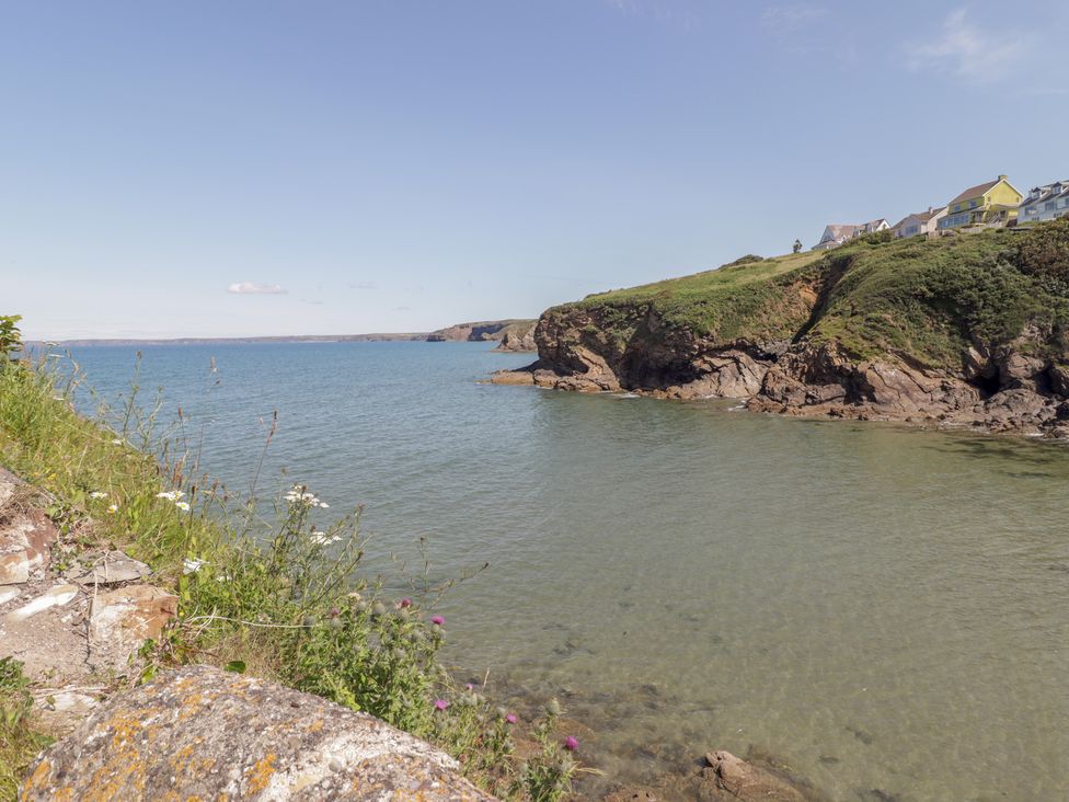 A shoreline with water and cliffs at Reef Retreat in Broad Haven