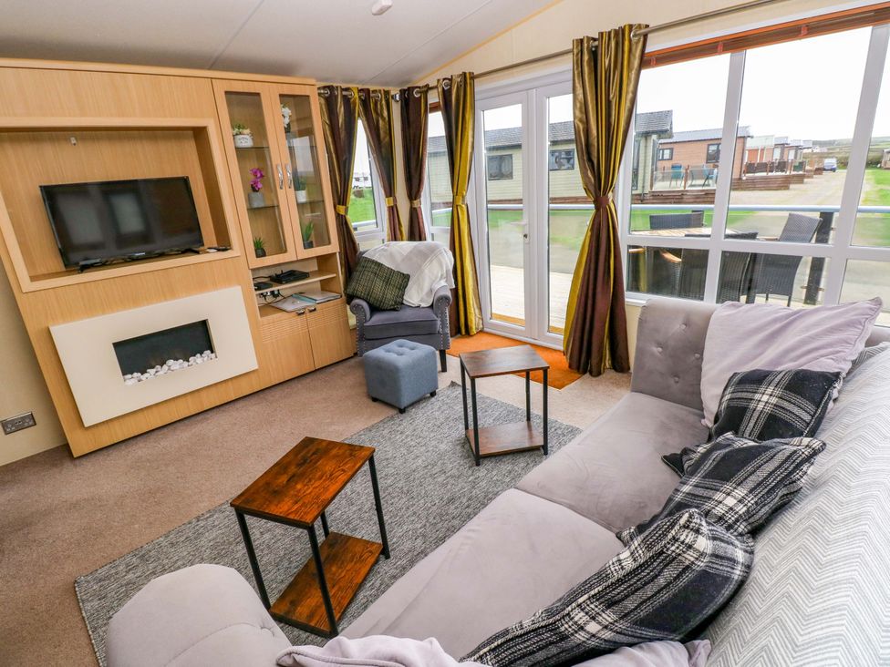 A living room with a TV and shelves at Reef Retreat in Little Haven