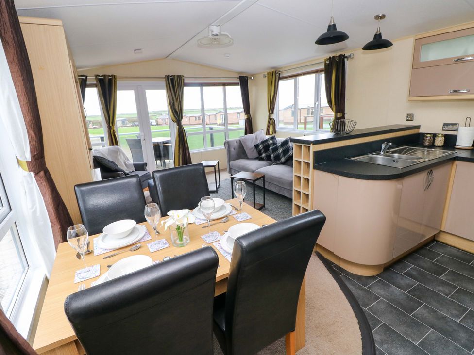 A dining room with a table set for meals and a sofa at Reef Retreat in Little Haven