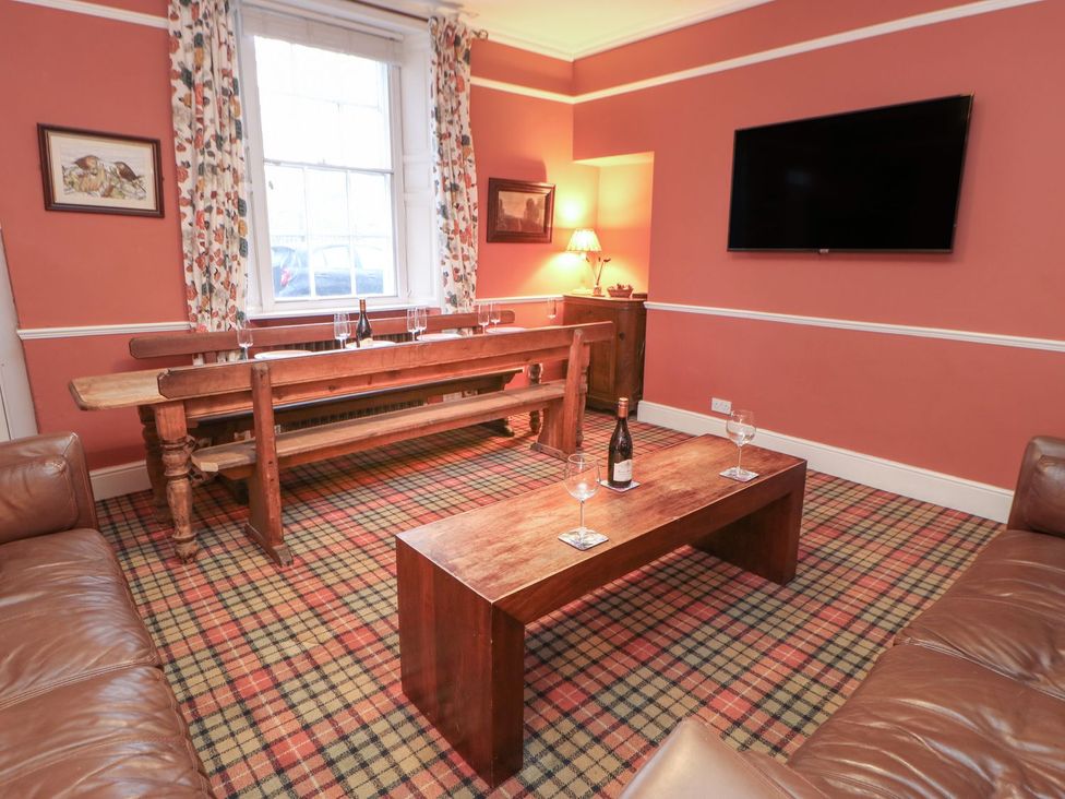 A living room with a dining table, sofa, and television at The Smithy in Barnard Castle