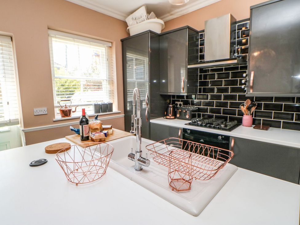 A kitchen with a sink, stove, and wine bottle at The Smithy in Barnard Castle