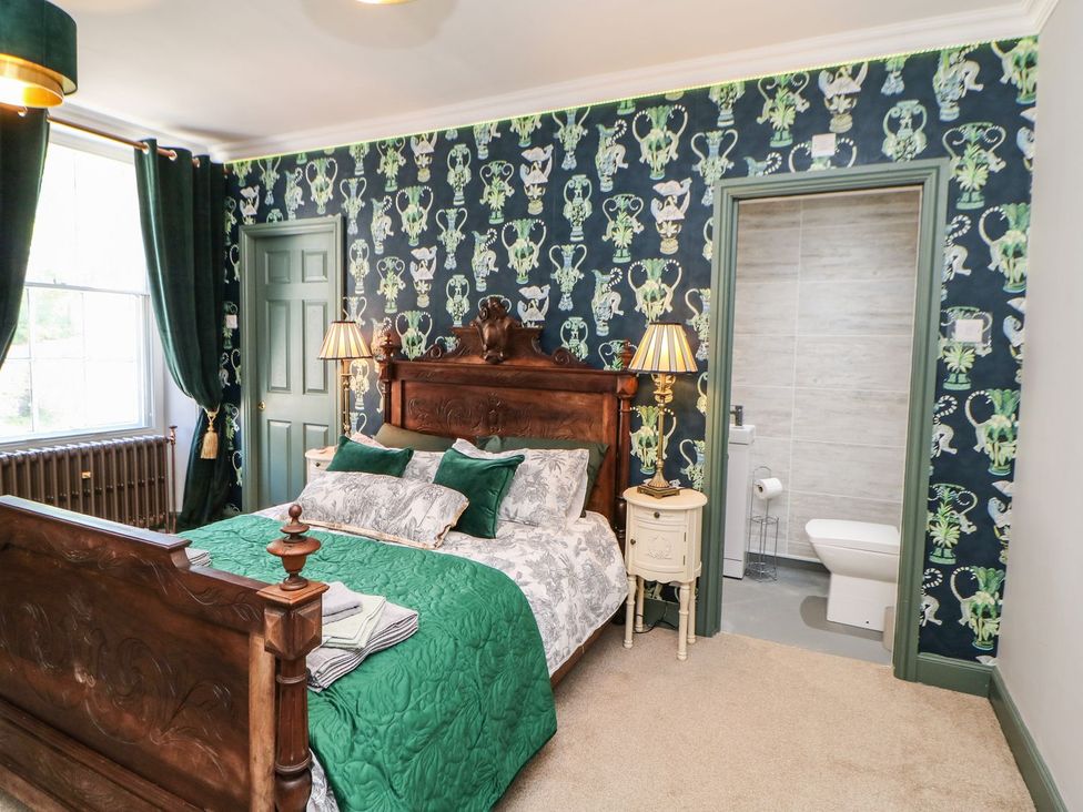 A bedroom with a bed, lamp and a door leading to a bathroom at The Smithy in Barnard Castle