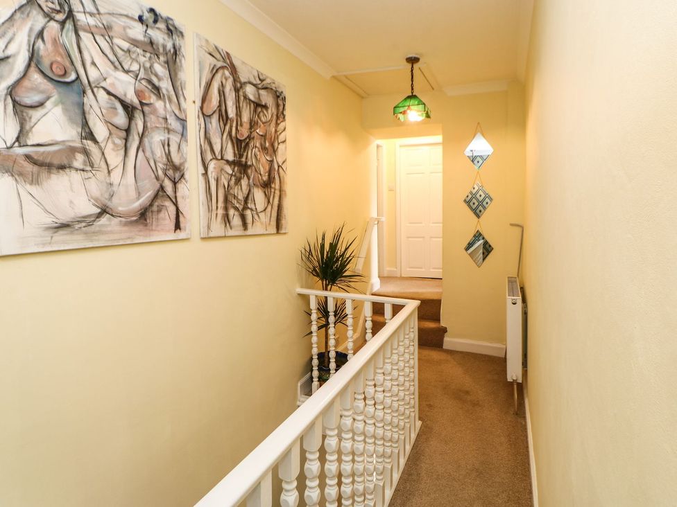 A hallway with paintings on the wall and a plant at The Smithy in Barnard Castle