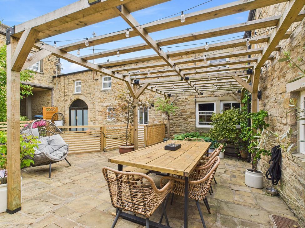 A garden with a table and chairs under a pergola at The Smithy in Barnard Castle