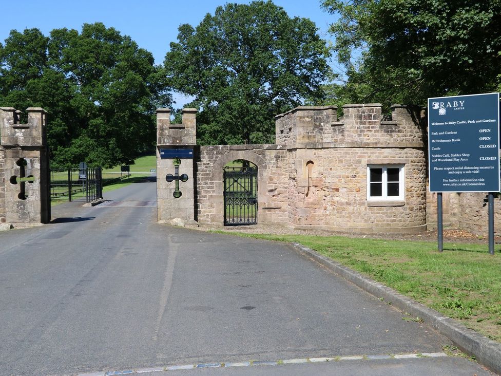 Gates leading to Raby Castle with a sign at Raby Castle Park and Gardens in Barnard Castle