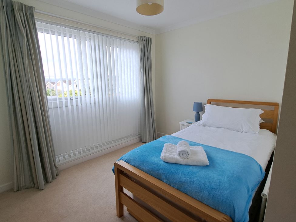 A bedroom with a bed and a bedside table at 30 Long Shepherds Drive in Newton near The Mumbles