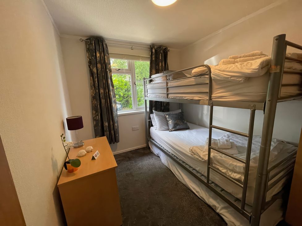 A bedroom with a bunk bed and dresser at Treetops Beech Hill 13, Fallbarrow Park near Bowness-On-Windermere