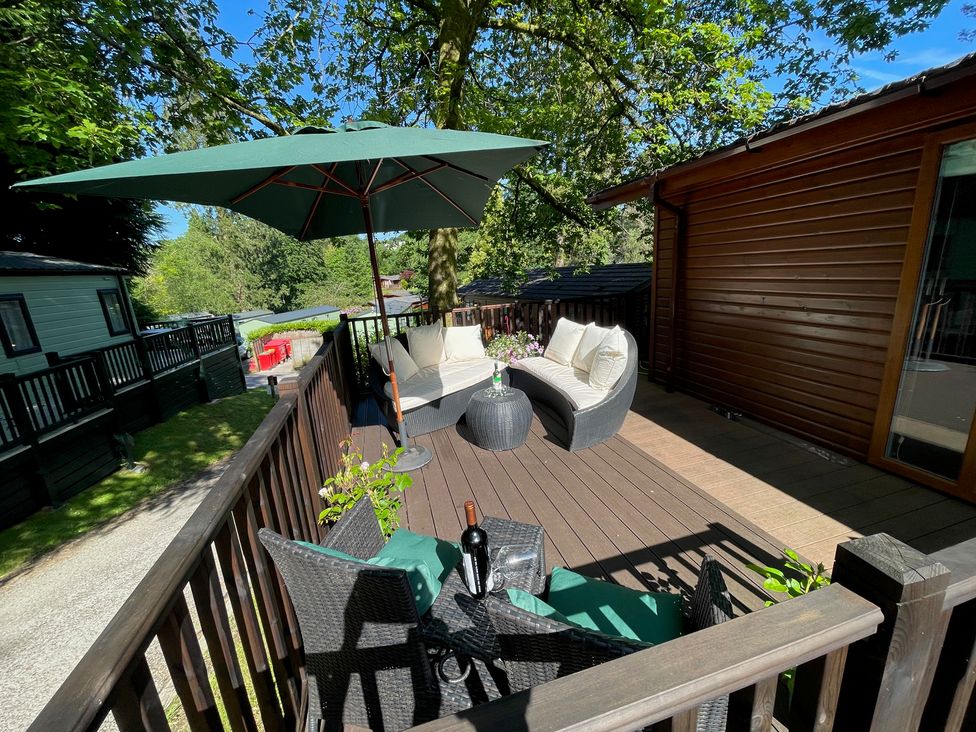 An outdoor space with furniture and an umbrella at Treetops, Beech Hill 13, Fallbarrow Park near Bowness-On-Windermere