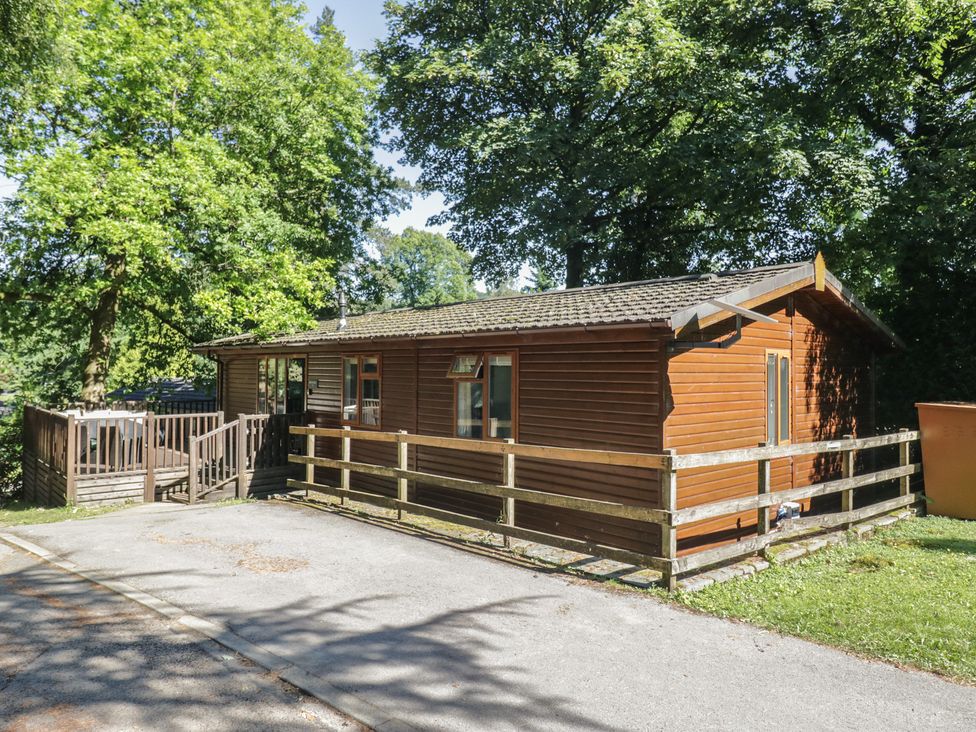 A cabin with decking and trees at Treetops, Beech Hill 13, Fallbarrow Park near Bowness-On-Windermere