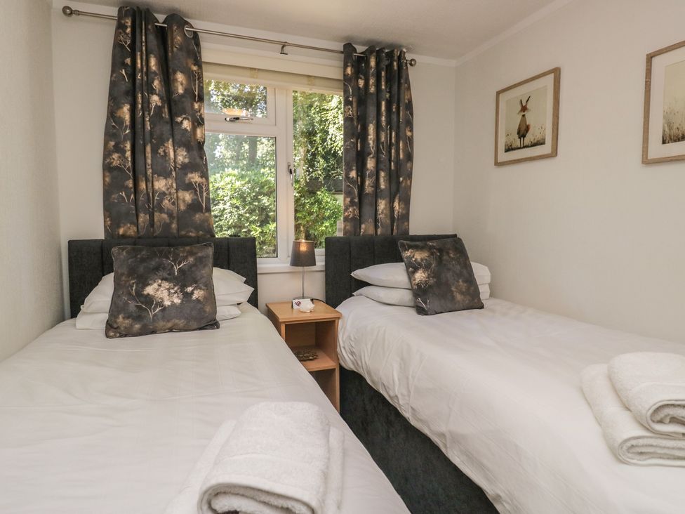 A bedroom with two beds and a window at Treetops, Beech Hill 13, Fallbarrow Park near Bowness-On-Windermere